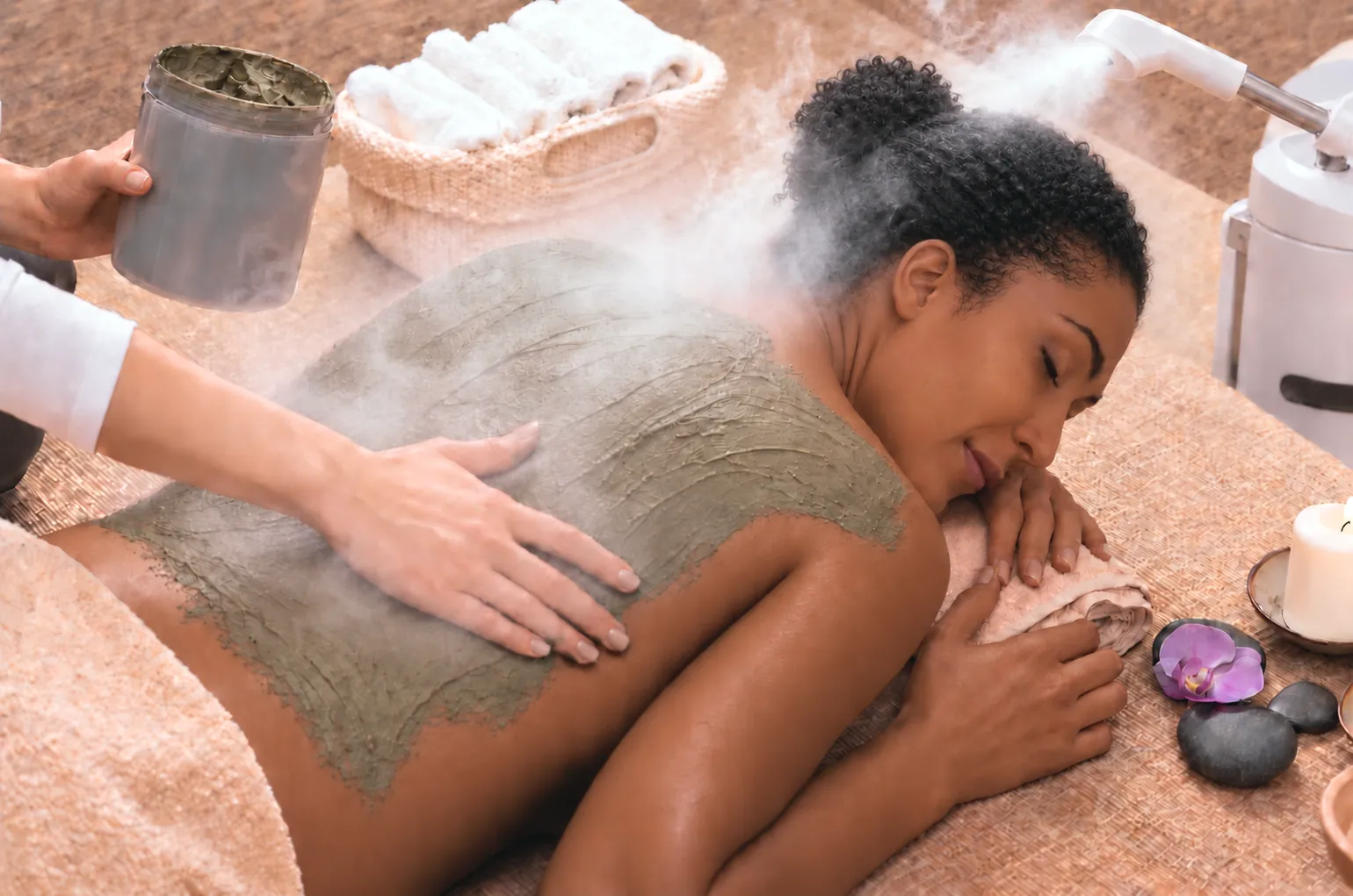 Clay masque and steam on a client’s back during a back facial