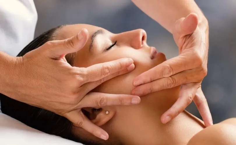 Hands massaging a client's face and jaw