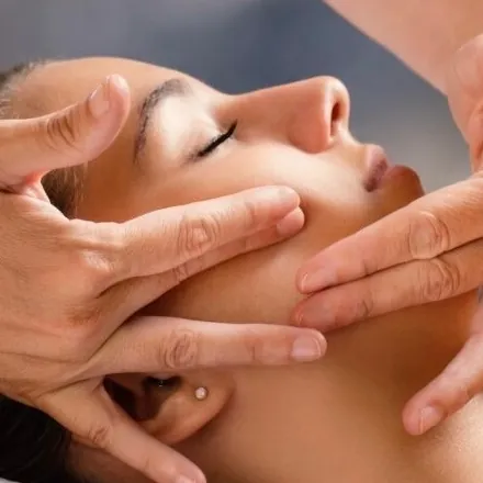 Hands massaging a client's face and jaw