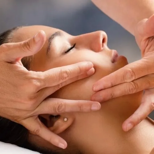 Hands massaging a client's face and jaw